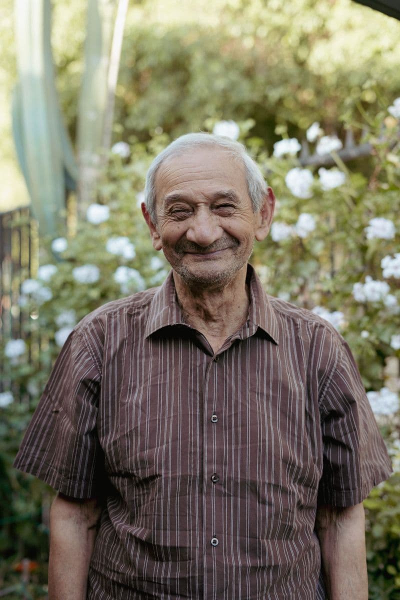 An older participant smiling in his garden.